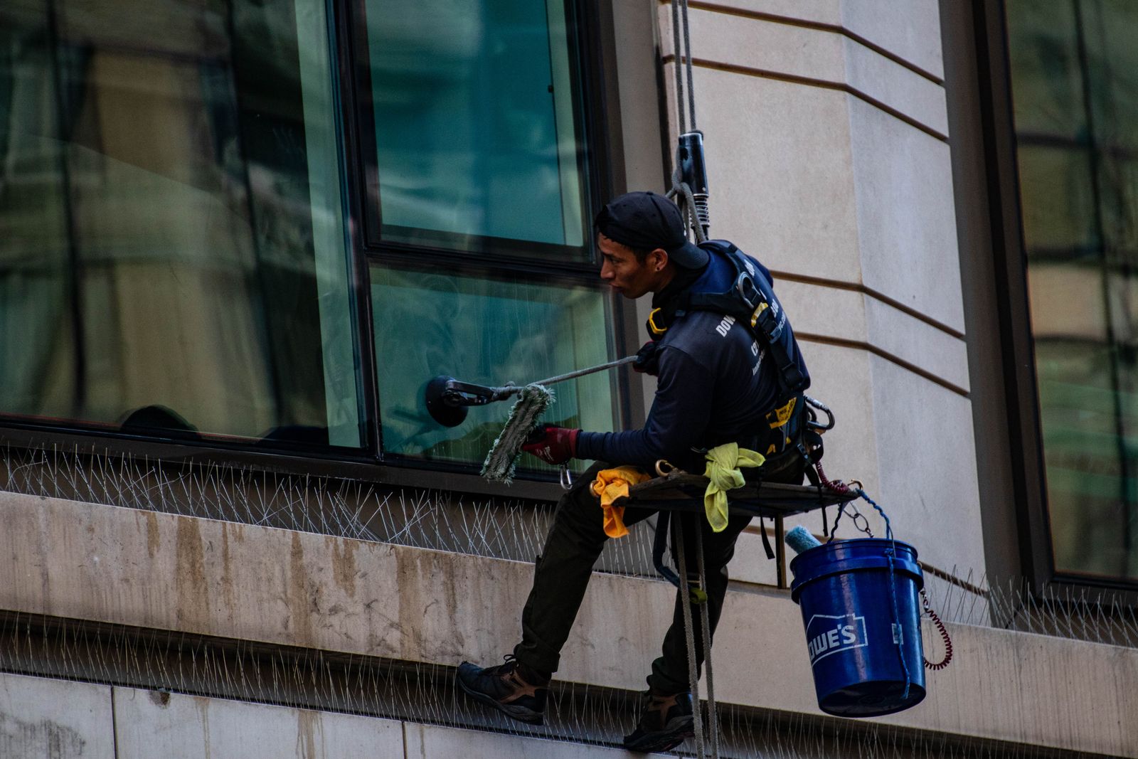 Technician on rope descent cleaning high-rise glass